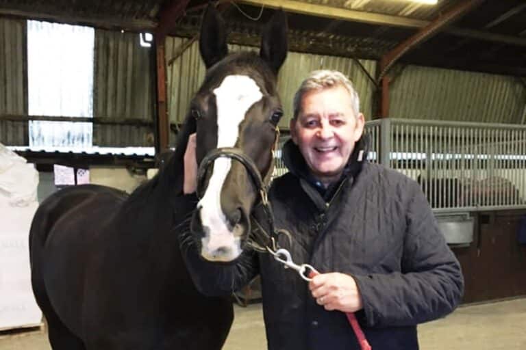 Image shows Mel Gee with racehorse in stables.