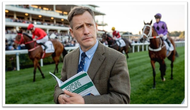 Image shows a man looking slightly confused at a race track.